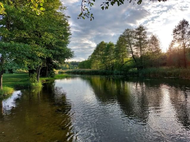 Malowniczy widok na wodę o zachodzie słońca – kajaki Czarna Hańcza startują z przystani AS-TOUR.